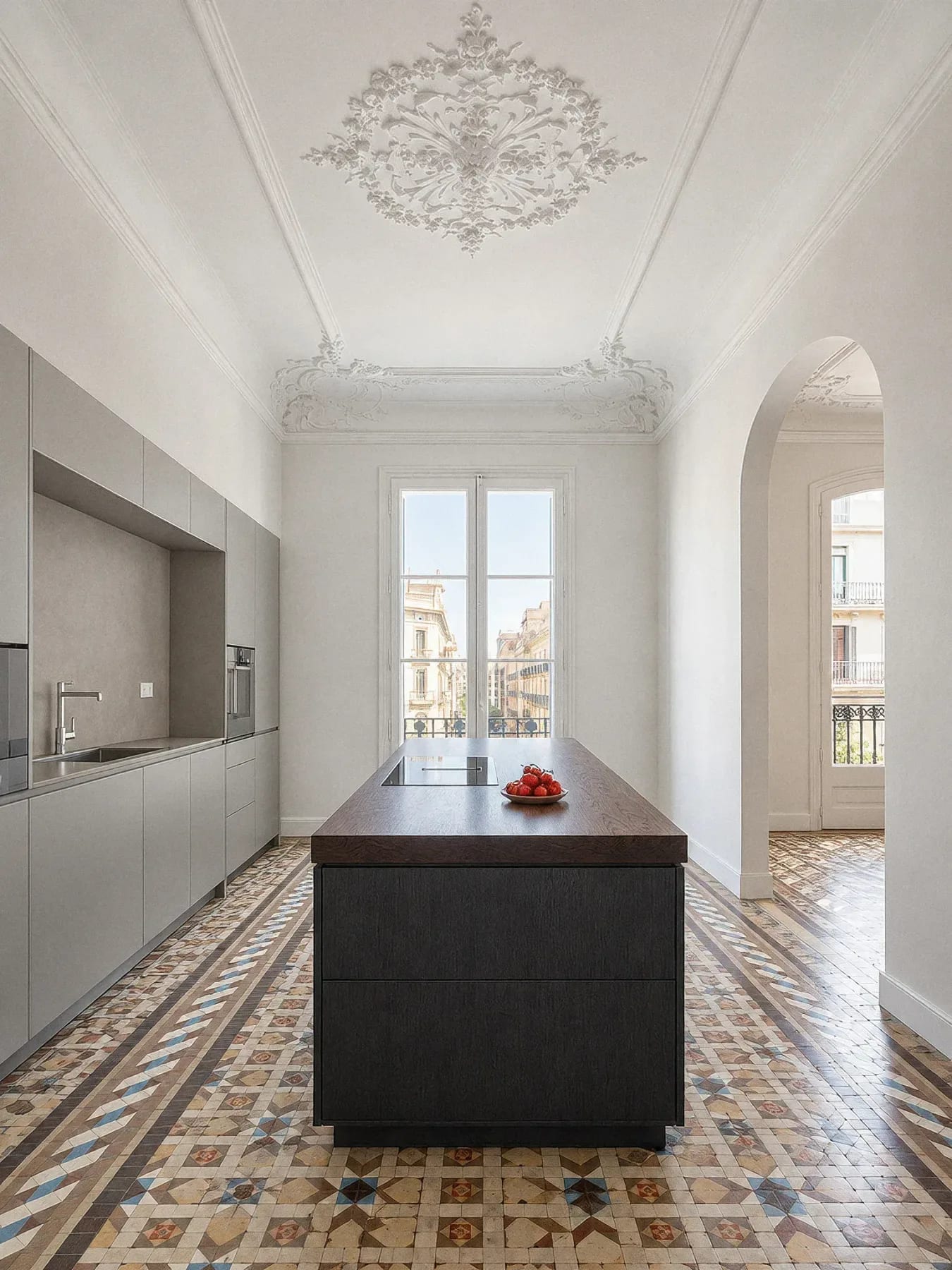 Cocina gris de líneas sencillas con isla de madera oscura sobre el mosaico Nolla restaurado